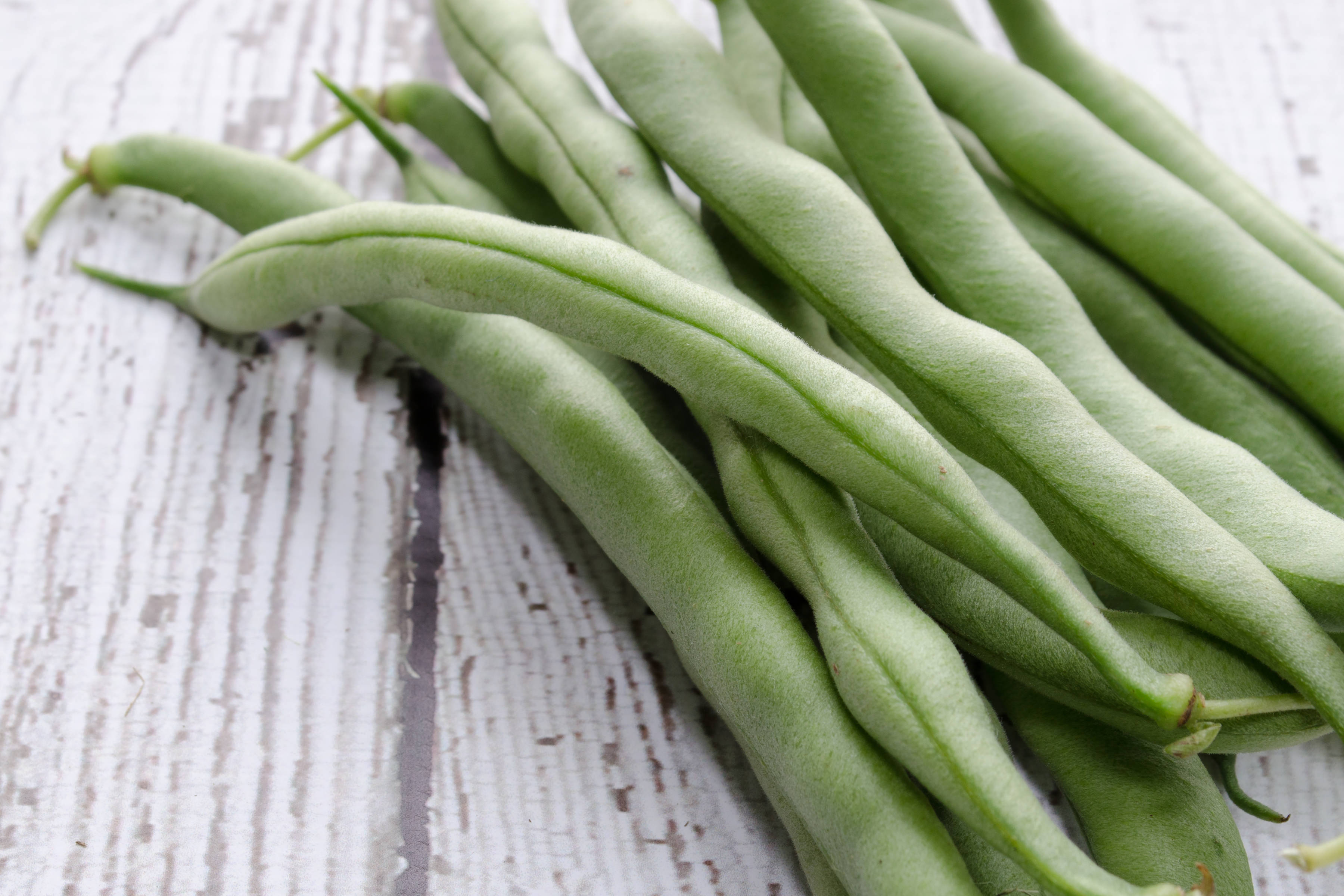 Stack of green beans on a wooden board. Photo: Linda Hall / iStock.